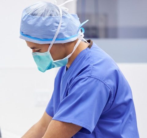 Male Surgeon Wearing Scrubs Washing Hands Before Operation In Hospital Operating Theater